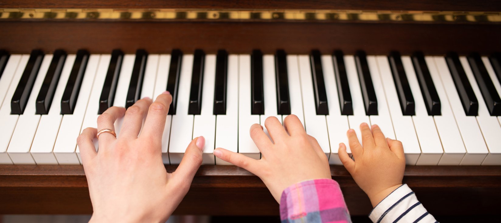 Hands of parents and children playing the piano